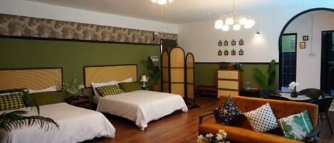 A hotel room with two beds, a sofa, a coffee table, and a decorative wall.