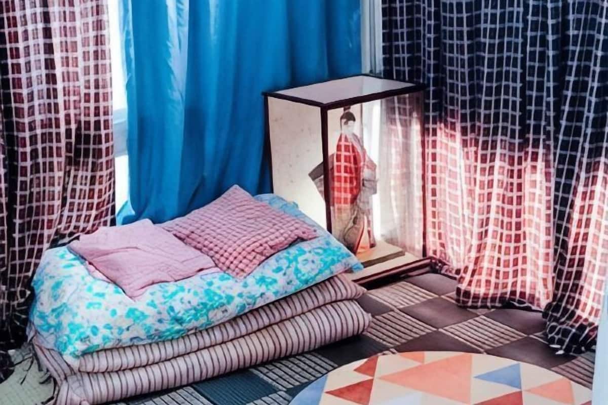 Une pièce avec un lit, des oreillers, une petite table et des rideaux.