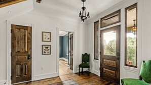 A spacious room with wooden flooring, a green chair, and a large window with a view of trees. - Large 6 bedroom, 6.5 bath restored Victorian home at Indiandale Springs (Reinholds)