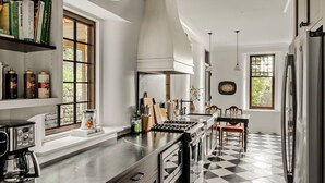 A modern kitchen with a black and white checkered floor, stainless steel appliances, and a central island. - Large 6 bedroom, 6.5 bath restored Victorian home at Indiandale Springs (Reinholds)