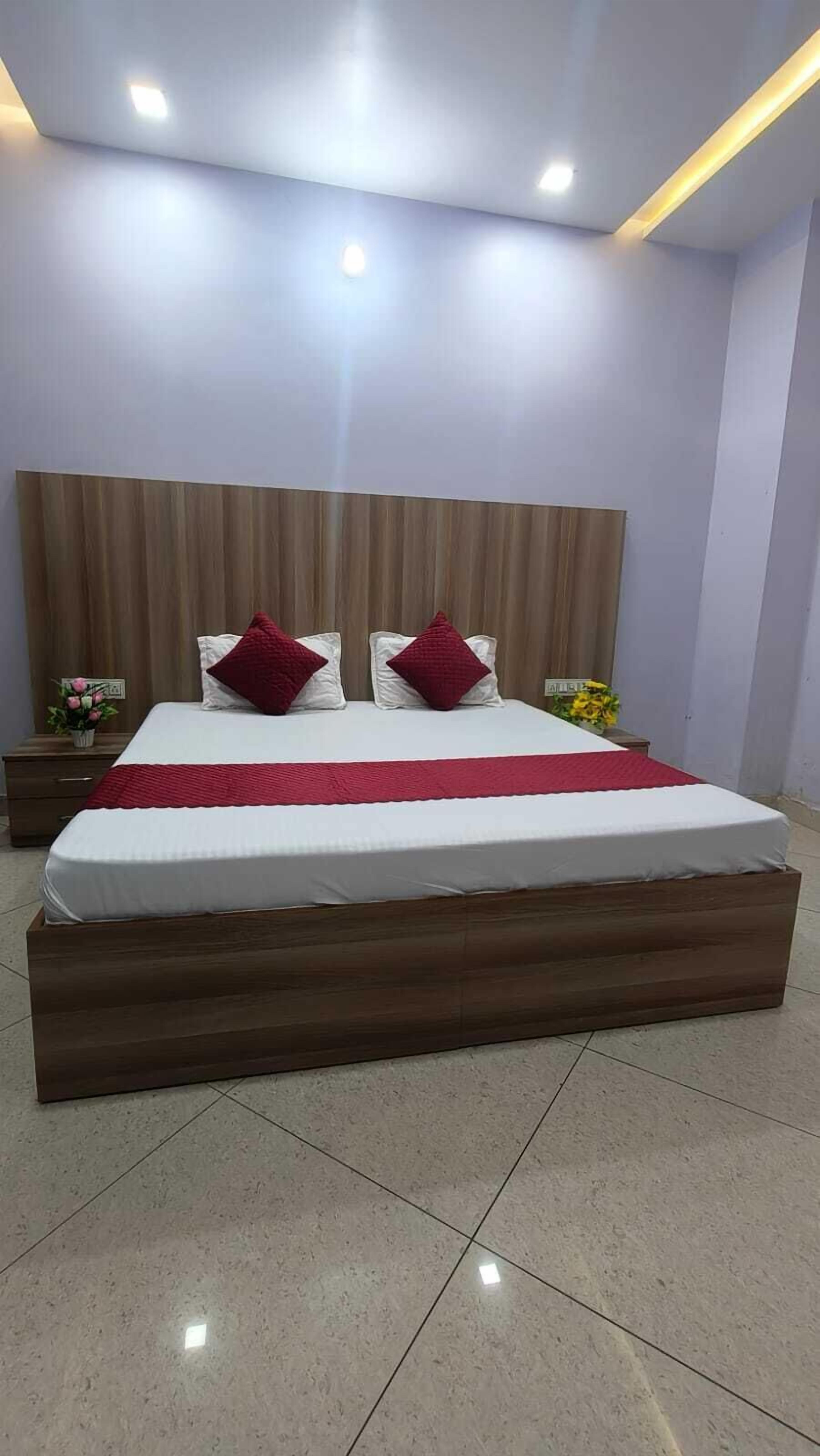 Un dormitorio moderno con una cama grande, cabecera de madera y una manta roja.