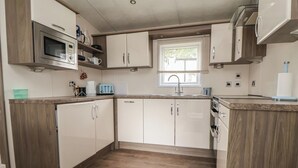 Eine kleine Küche mit Holzausstattung, einer Mikrowelle, einem Toaster und einem Fenster, das für natürliches Licht sorgt.
