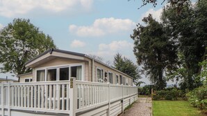 Ein Bungalow mit weißer Fassade, einem Schotterweg und einem weißen Zaun.