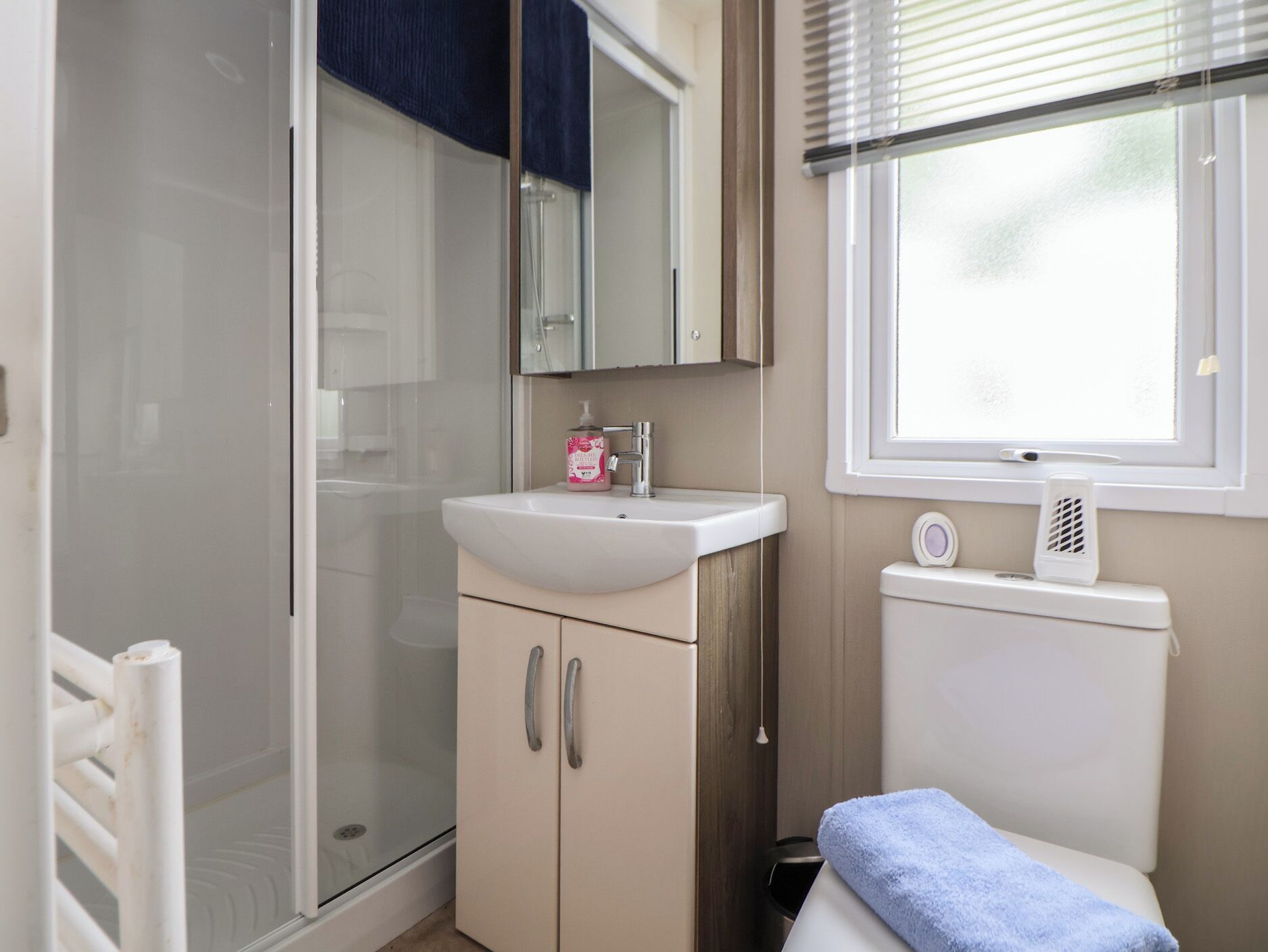 Un baño con ducha, lavamanos, inodoro y ventana.