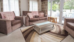 Ein Wohnzimmer mit zwei Sofas, einem Couchtisch und Blick ins Freie durch große Fenster.