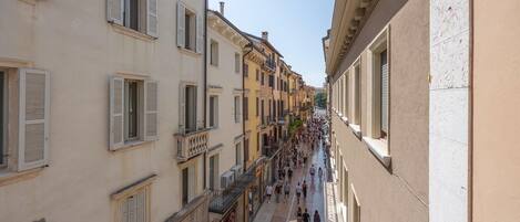 A narrow street lined with multi-story buildings, featuring balconies and ground-level shops.