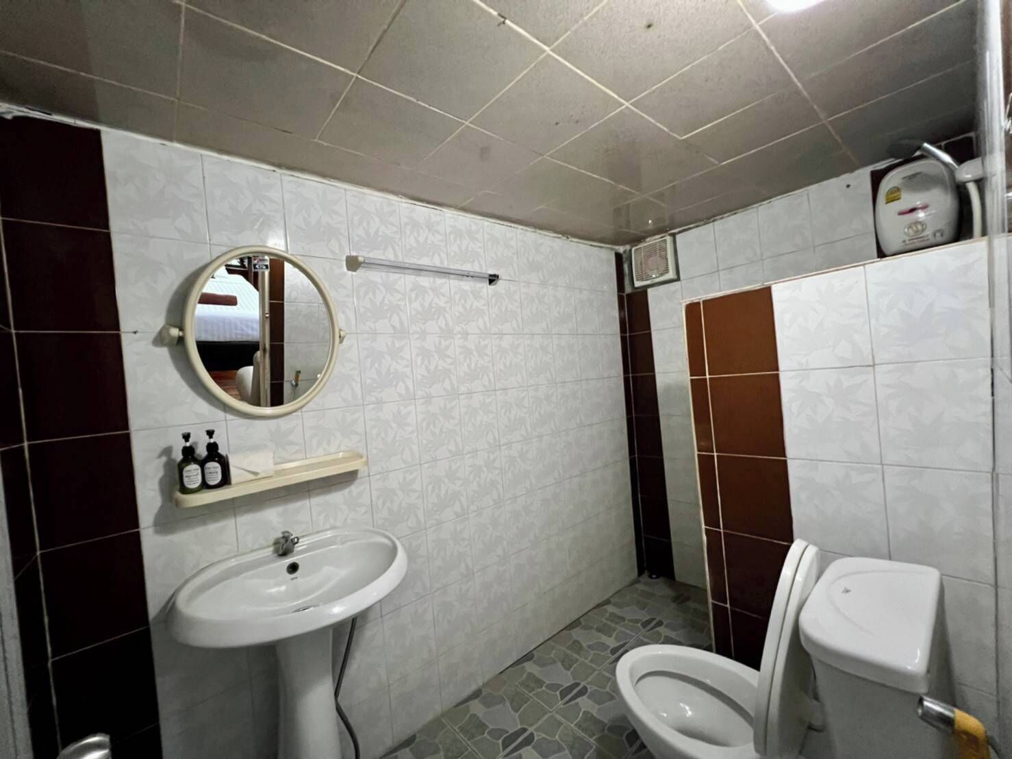 A bathroom with a sink, mirror, toilet, and a shelf with toiletries.