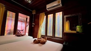 A room with two beds, a wooden ceiling, an air conditioning unit, and colorful curtains. - Greenplace-Samed Seahorse (Rayong)
