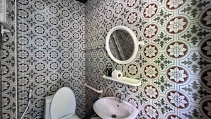 A bathroom with patterned tiles, a toilet, a sink, and a mirror. - Greenplace-Samed Seahorse (Rayong)