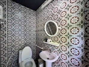 A bathroom with patterned tiles, a toilet, a sink, and a mirror. - Greenplace-Samed Seahorse (Rayong)