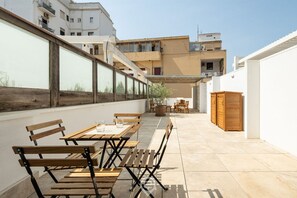Une terrasse extérieure avec des tables et des bancs en bois, une plante en pot et un meuble en bois.