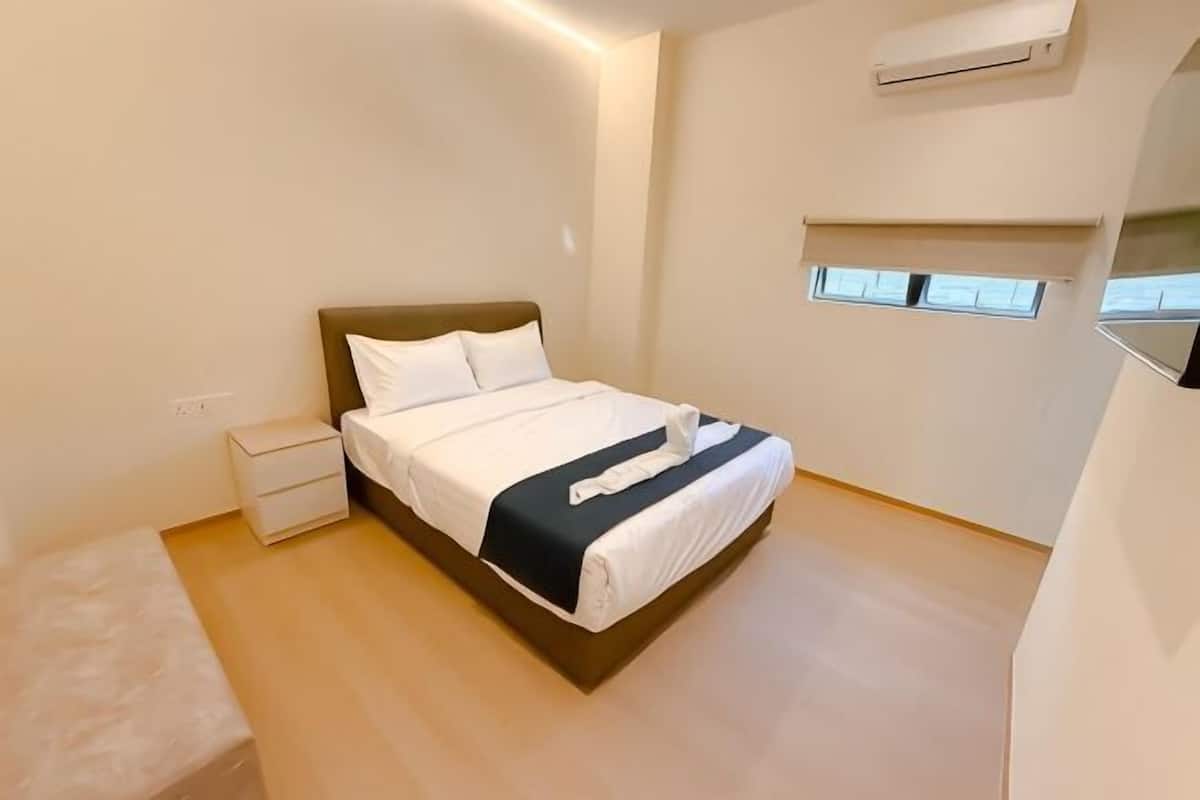 A bedroom with a bed, bedside table, and a window.