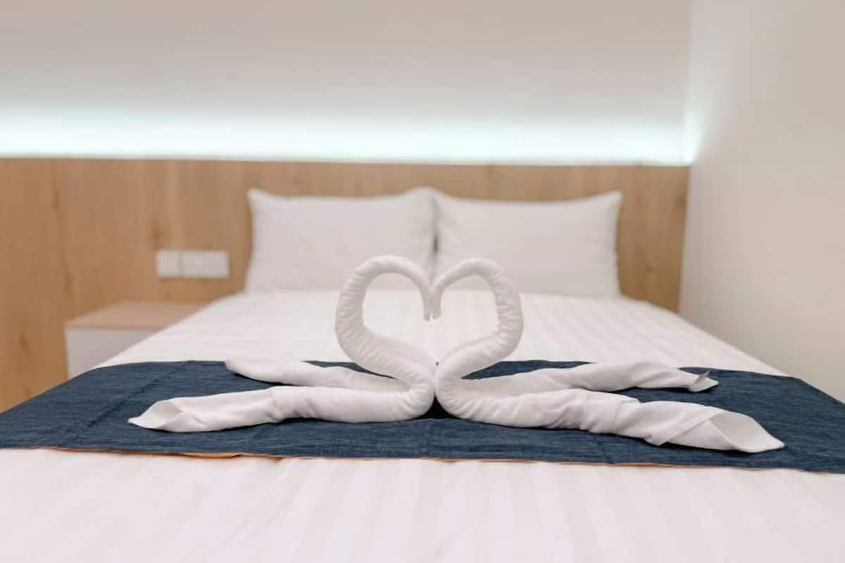 Un lit avec une disposition de serviettes en forme de cœur sur un couvre-lit bleu.