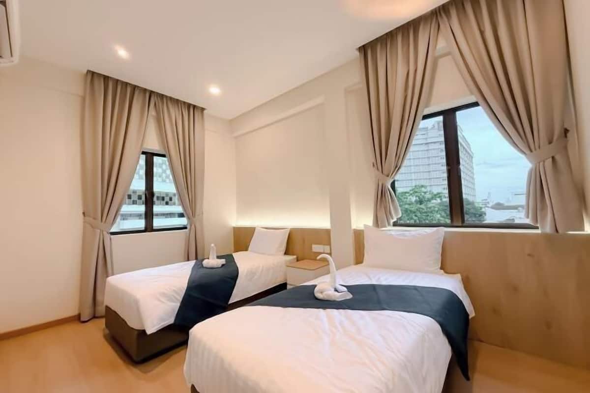 Une chambre d’hôtel avec deux lits, une vue sur la ville et une fenêtre avec des rideaux.