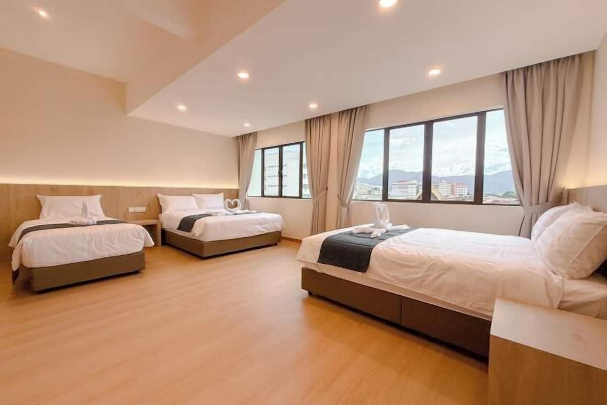 Une chambre d’hôtel avec trois lits, une grande fenêtre donnant sur la ville et un plancher en bois.