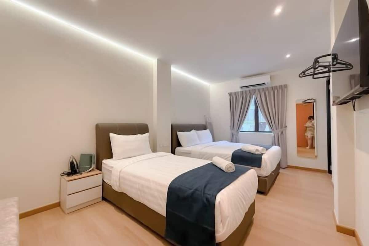 Une chambre d’hôtel moderne équipée de deux lits, d’un téléviseur à écran plat, d’une table de chevet avec une lampe et d’un grand miroir.