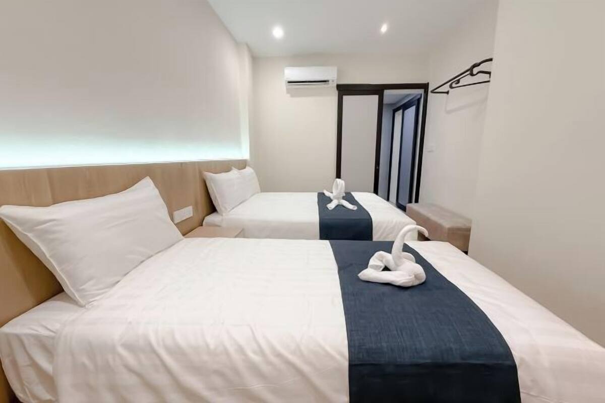Une chambre d’hôtel avec deux lits, une table de chevet, un appareil de climatisation et un miroir.