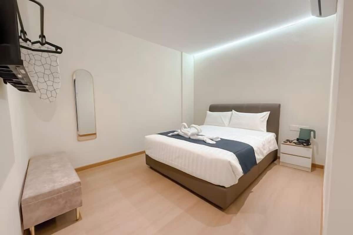 Une chambre à coucher moderne avec un lit, une table de chevet et un petit banc.
