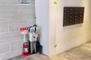 Eine Ecke mit einem Feuerlöscher, einem Schild und einem Regall für Regenschirme.