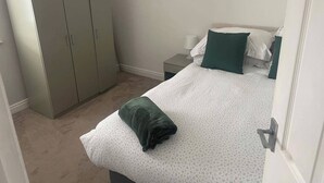 A bedroom with a bed, a wardrobe, a nightstand, and a door. - Horsforth Apartment Leeds Bradford Airport (Leeds)