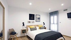 Une chambre à coucher moderne, dotée d’un grand lit, de tables de chevet, d’une chaise et d’œuvres d’art accrochées aux murs.