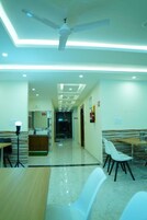 A hotel lobby with a modern design, featuring a reception desk, seating area, and a ceiling fan.