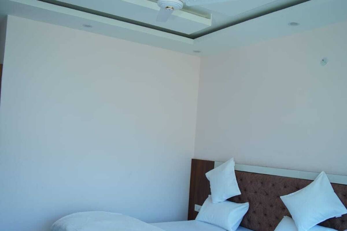 A bedroom with a bed, white bedding, a ceiling fan, and a wooden headboard.