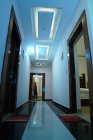 A hotel hallway with a reflective floor, a person walking, and a door leading to a room.