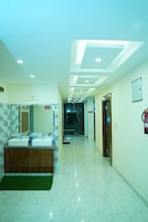 A hotel corridor with a double sink vanity, a ceiling with recessed lighting, and a fire extinguisher on the wall.