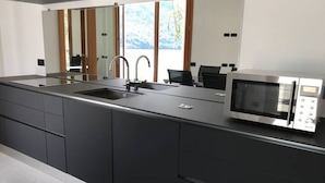 A modern kitchen with a large island, stainless steel appliances, and a view of the outdoors.