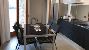 A compact kitchen with a dining area, featuring a table and chairs, a refrigerator, and a stove.