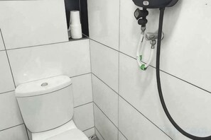 A white toilet with a paper towel dispenser and a black hose attached to the wall. - E-Hotel @ Kulim (Kulim)