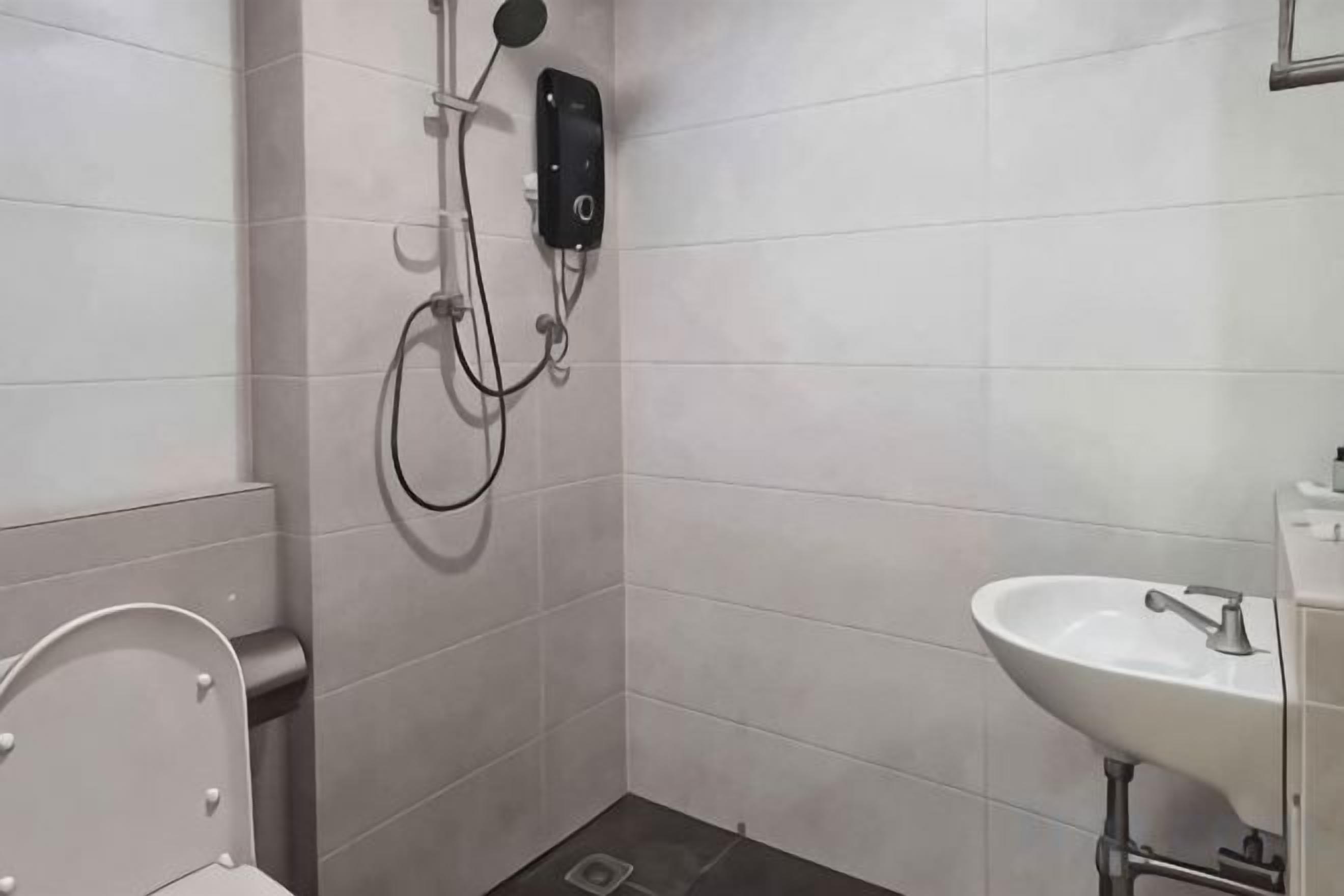 Une salle de bain équipée de toilettes, d’un lavabo et d’une douche avec un pommeau de douche amovible.