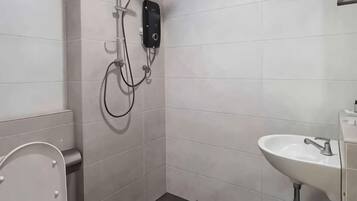 Une salle de bain équipée de toilettes, d’un lavabo et d’une douche avec un pommeau de douche amovible.