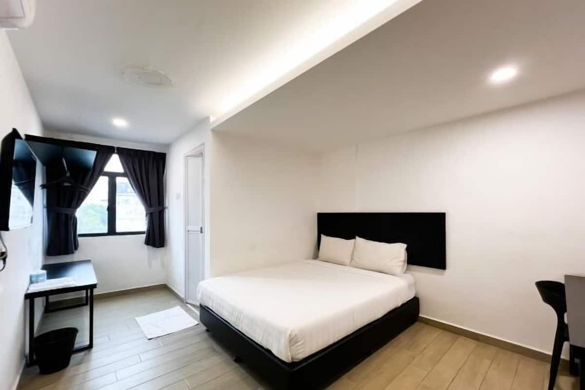 A modern hotel room with a bed, a desk, and a chair.