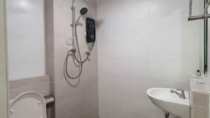 Une salle de bain avec des toilettes, un lavabo et une douche.