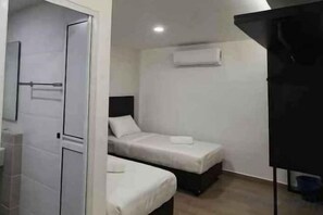 A small, compact room with two beds, a door, and a wall-mounted air conditioning unit. - E-Hotel @ Kulim (Kulim)