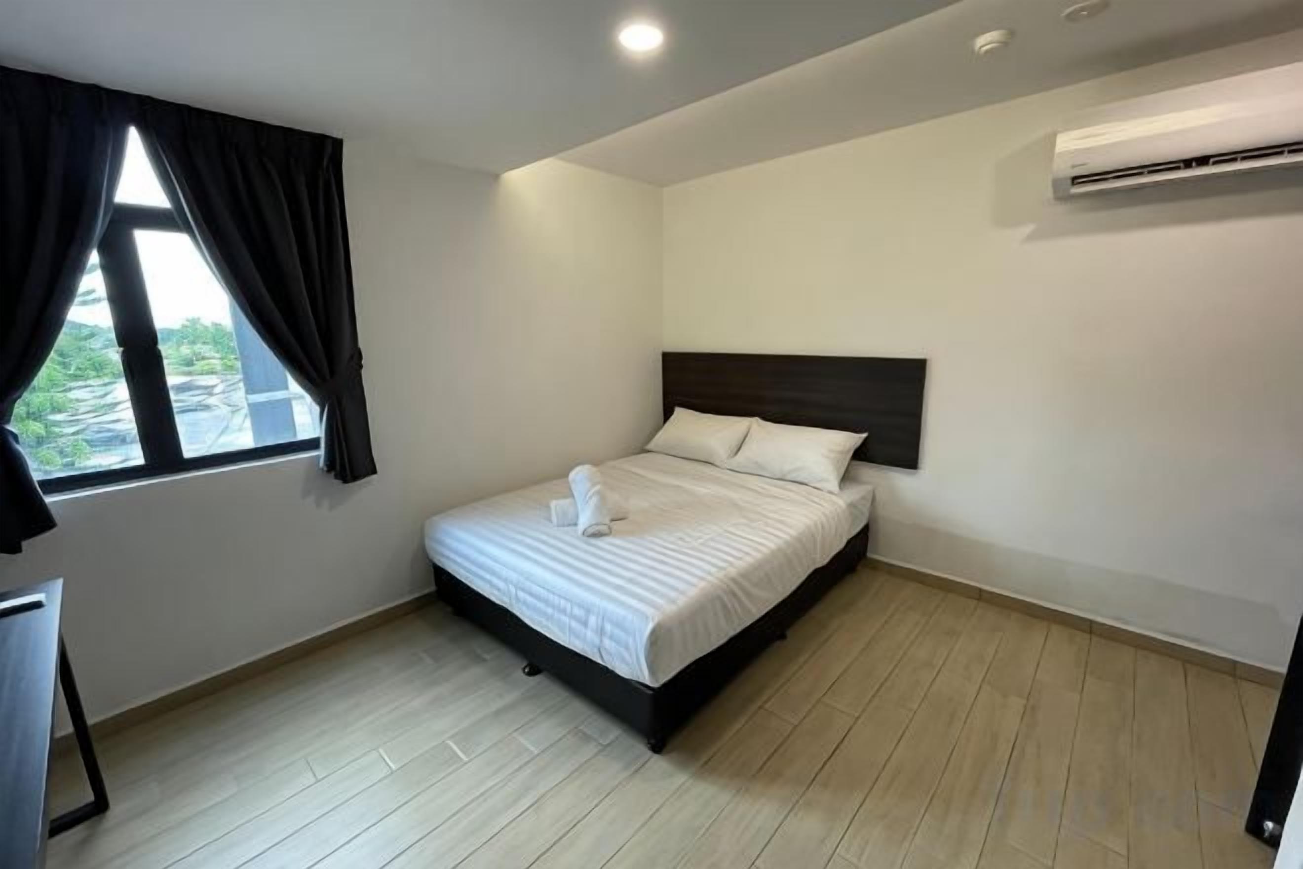 A bedroom with a bed, a window with curtains, an air conditioning unit, and a desk.