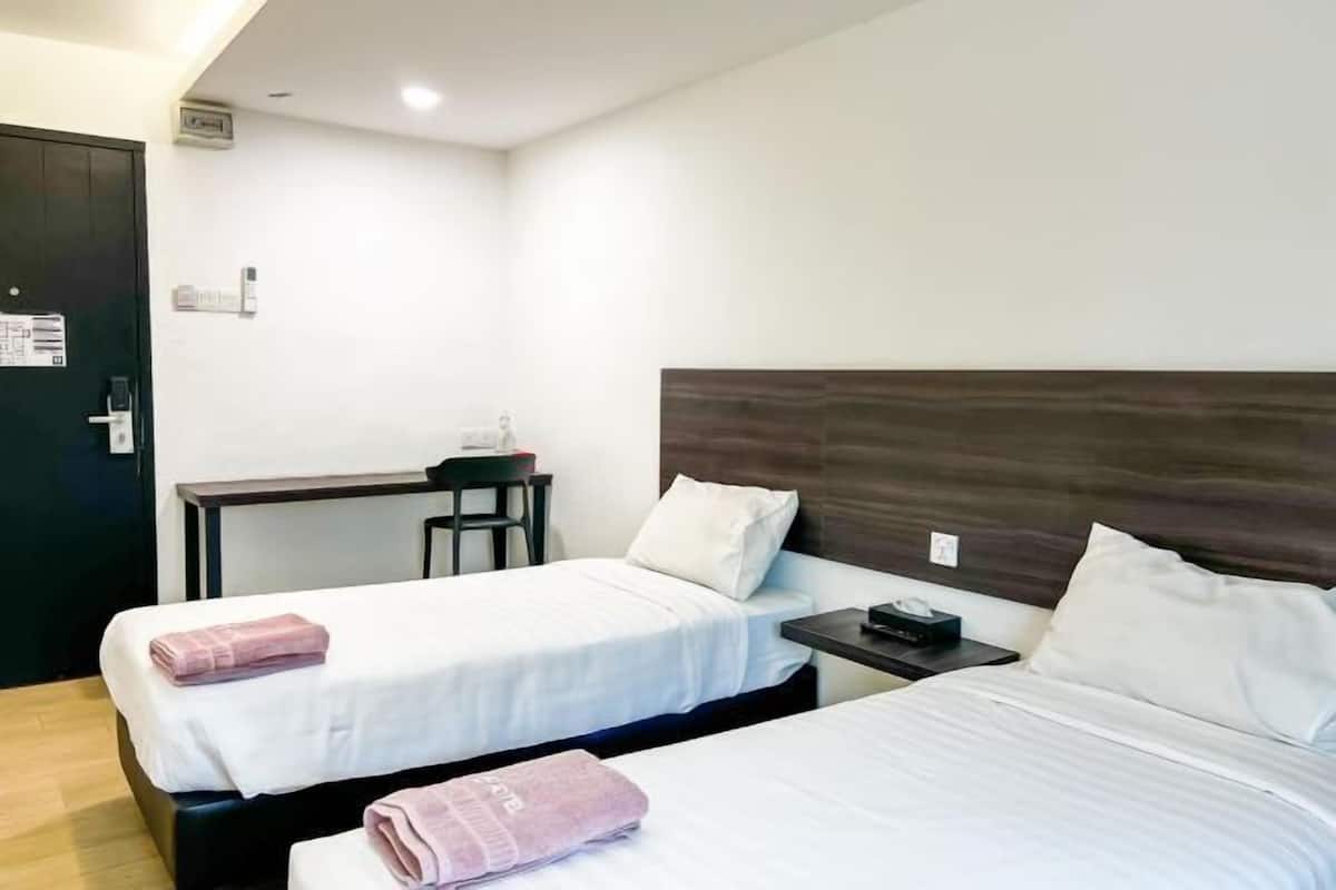A hotel room with two beds, a desk, and a chair.