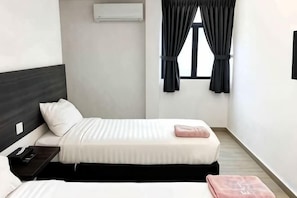 A hotel room with two beds, a small table, and a window with curtains. - E-Hotel @ Kulim (Kulim)