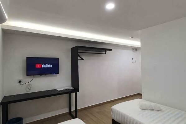 A room with a bed, a desk, a TV mounted on the wall, and a hanging rack. - E-Hotel @ Kulim (Kulim)