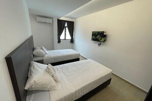 A bedroom with two beds, a TV mounted on the wall, and a window with curtains. - E-Hotel @ Kulim (Kulim)
