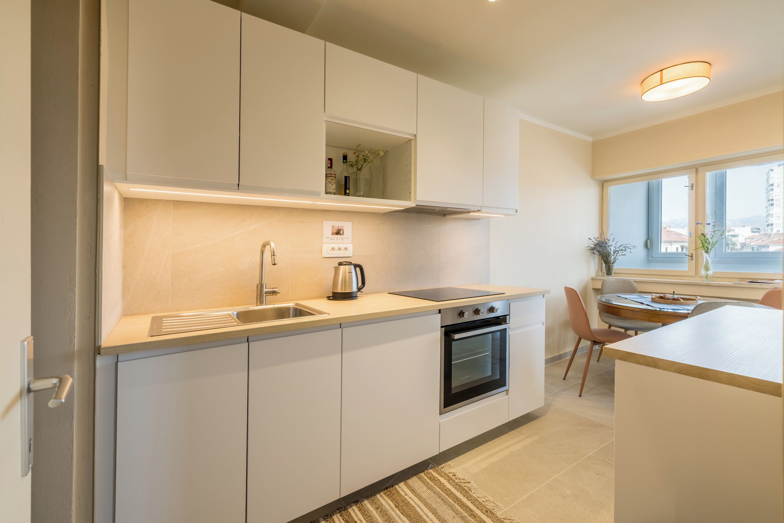 Una cocina moderna con horno integrado, un lavamanos y una ventana con vistas a la ciudad.