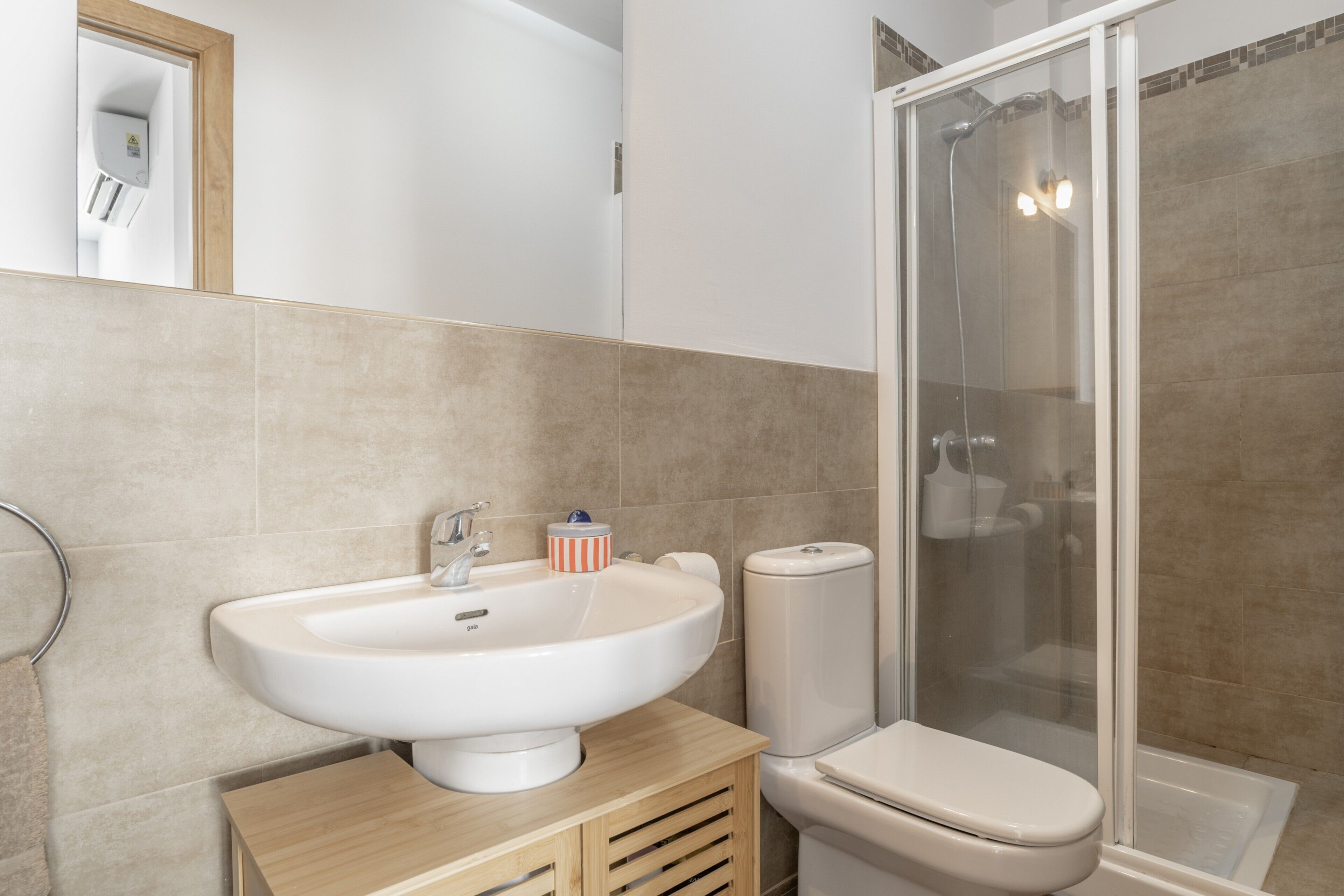 A bathroom with a white sink, toilet, and glass shower enclosure.