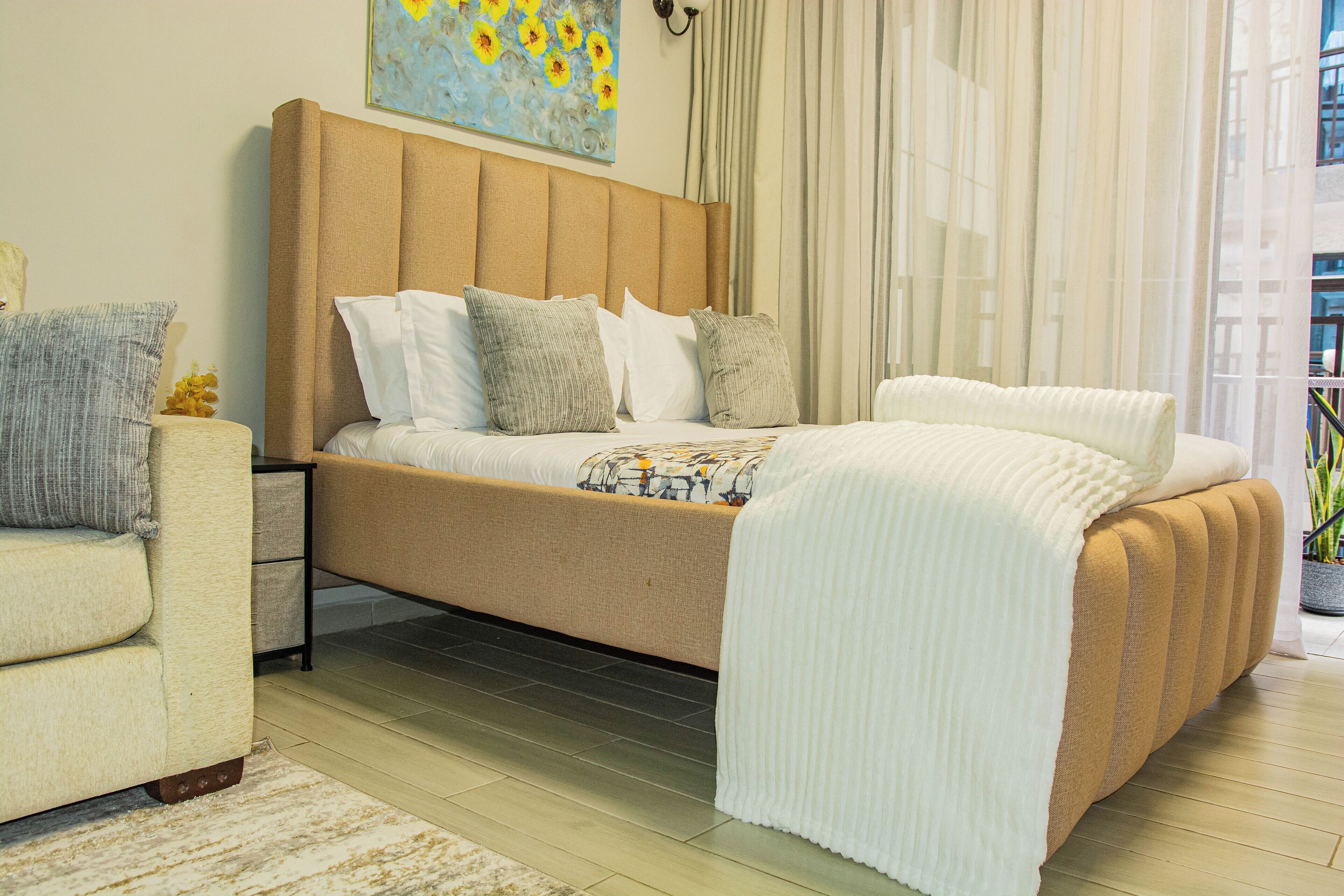 Un dormitorio moderno con una cama grande, un sofá y una mesita de noche.