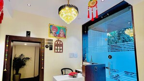 A reception area with a modern desk, a chandelier, and a glass partition with a view. - Shubh Laxmi Residence (Ajmer)