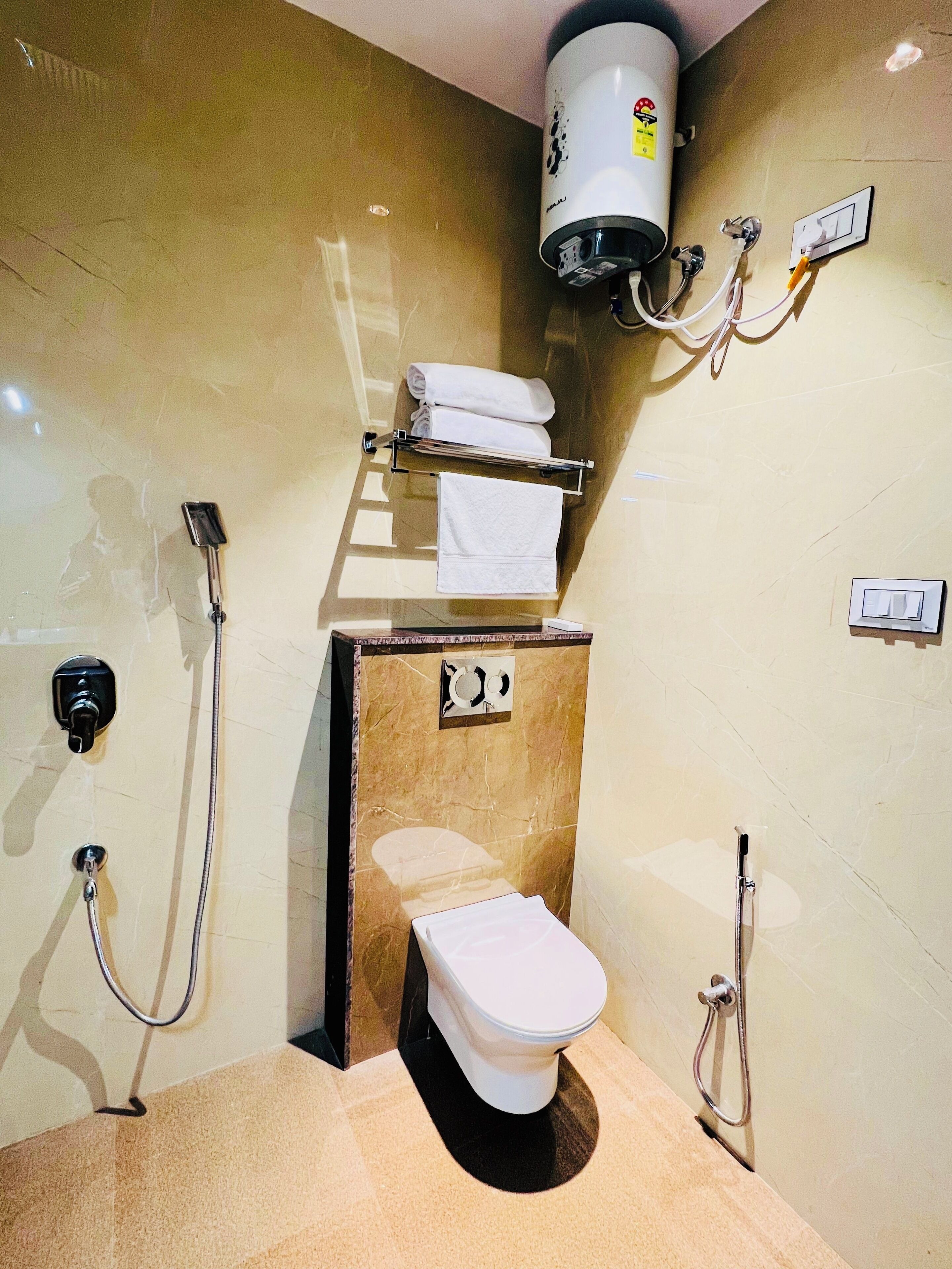 Et badeværelse med toilet, håndklædestang, brusebad og en håndtørrer.