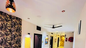 A hallway with a patterned wall, a ceiling fan, and a blue sofa. - Shubh Laxmi Residence (Ajmer)