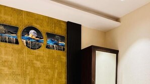 A hotel room with a bed, pillows, a nightstand, a lamp, and a large mirror. - Shubh Laxmi Residence (Ajmer)