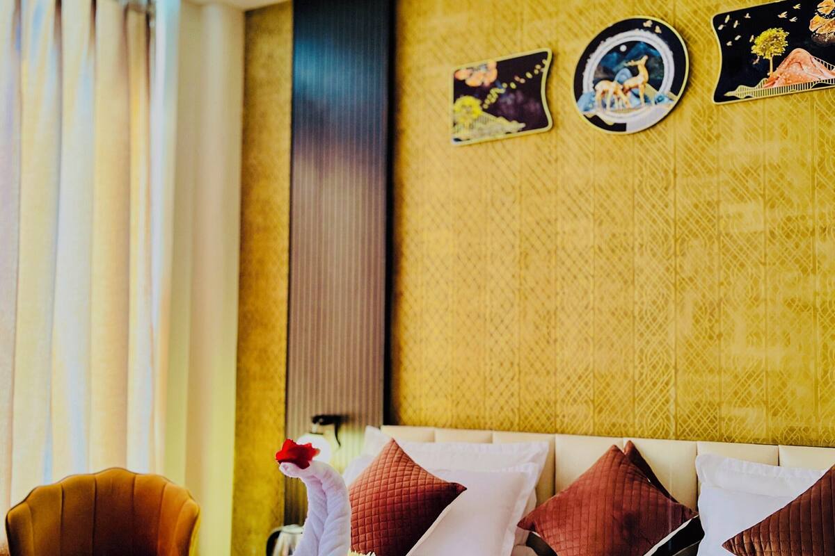 A hotel room with a bed, pillows, a chair, and decorative wall art.